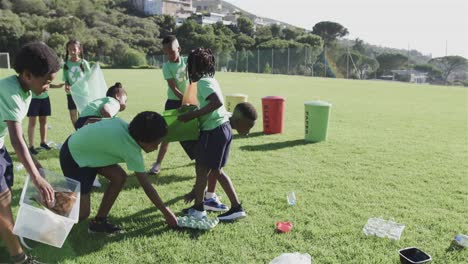 happy diverse schoolchildren wearing recycle tshirts cleaning sports field at elementary school