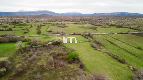 a descending aerial pushing towards the stone arches of the ancient ruins of burnum, an archaeological site that used to be a roman legion camp and town near krka national park in dalmatia, croatia