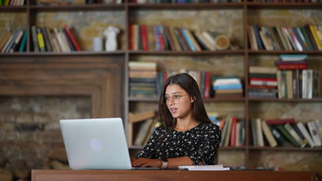 una mujer joven estudiando en una biblioteca.