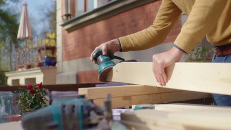 the craftsman holding the wood and sanding them with a grinding machine