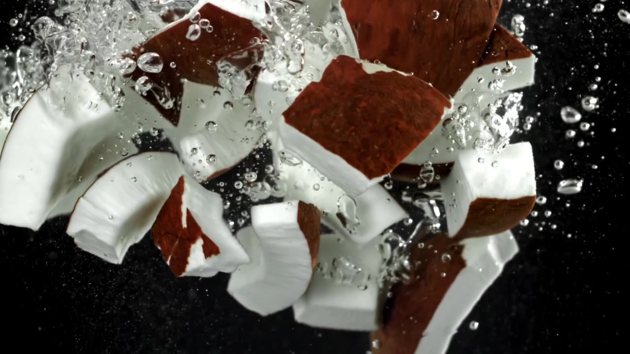 Pezzi di cocco fresco che schizzano nell'acqua con bolle