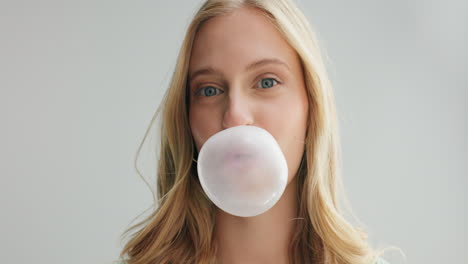 una mujer soplando un chicle.
