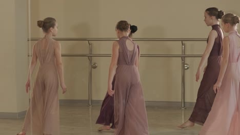 a group of young ballet students in black dancewear practicing positions in a spacious ballet studio with wooden flooring and wall-mounted barres. focused expressions and synchronized movements.