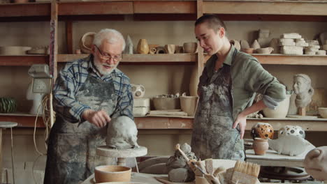 senior potter and young student discussing a sculpture