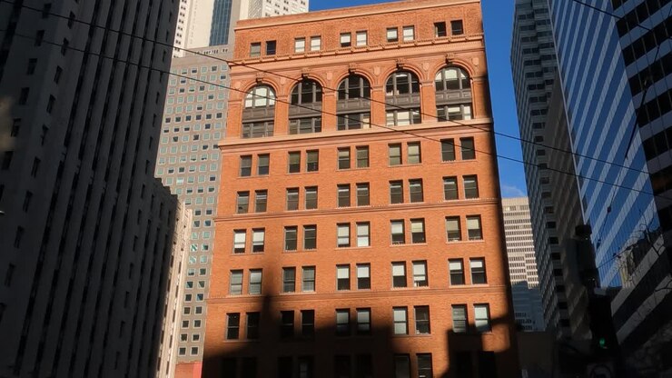 Vecchio edificio per uffici sotto i grattacieli di San Francisco, California, USA. Vista da Market Street, POV passeggero auto
