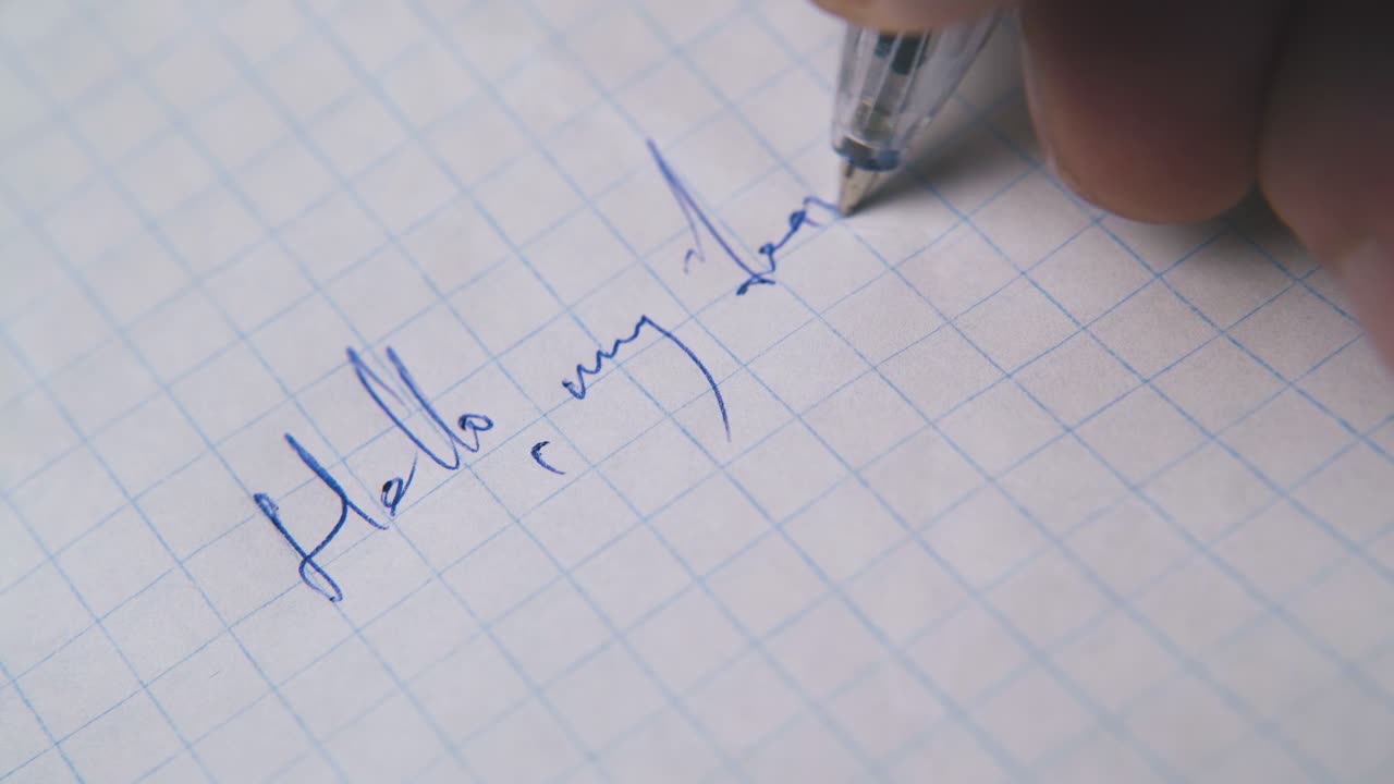 한 남자가 체크된 종이에 파란색 펜으로 친구에게 편지를 쓴다.