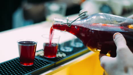 Barman-pouring-wine-from-bottle-into-glasses-on-counter.-Preparing-for-party