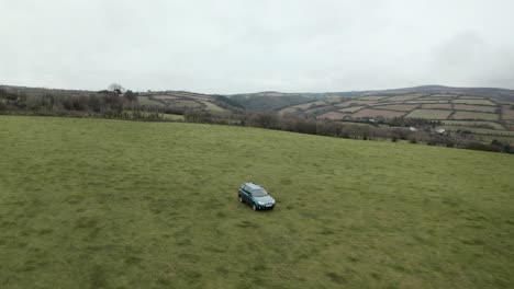 dolly back aerial drone shot of farmer driving 4x4 around an empty field
