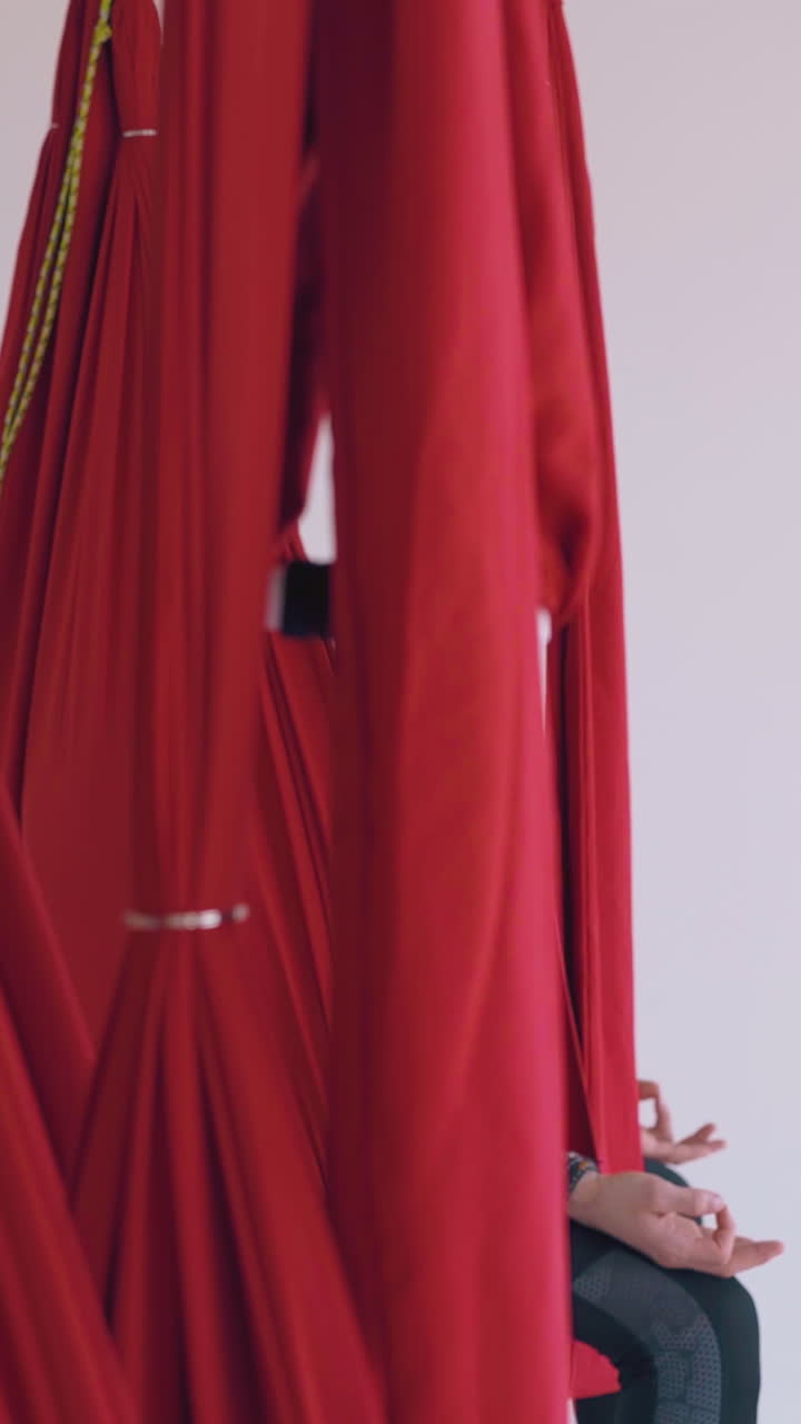 concentrated on meditation women group and alone man relax in special fly yoga hammocks in spacious modern gym closeup