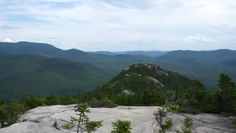 A-panning-shot-of-Welch-Dickey-mountains-with-a-green-mountain-and-rock-in-the-foreground-as-mountains-stand-against-the-skyline