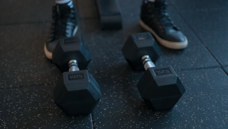 person on the gym with two dumbbells on the floor