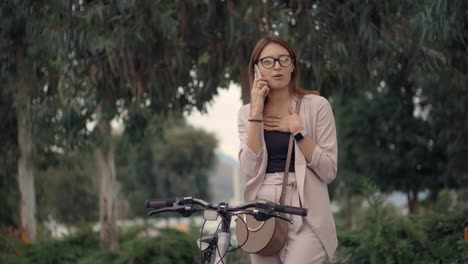 woman on phone beside bicycle in park