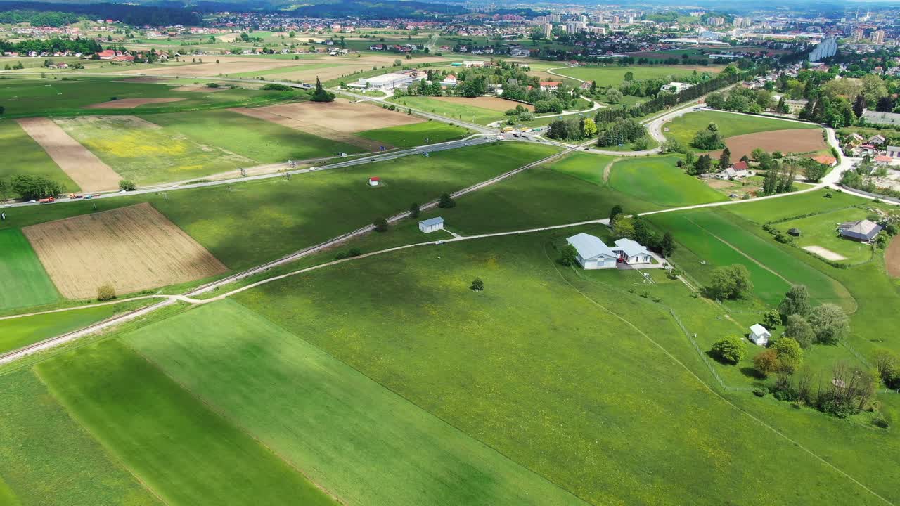 Flyover above fertile, green fields towards city of Celje, Slovenia