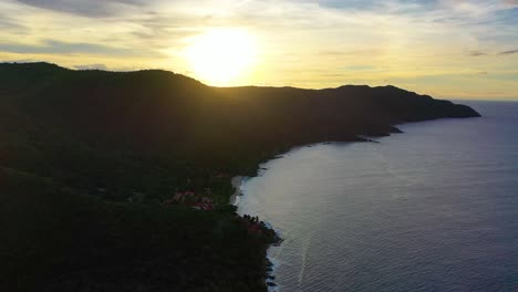 breathtaking drone footage of a colorful sunset over st. croix, where the sea reflects warm tones and the silhouette of an island peninsula creates a striking scene against the glowing sky