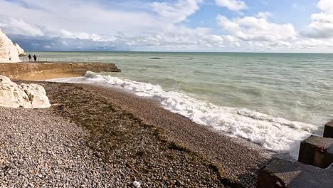 waves hitting pebbled shore near chalk cliffs