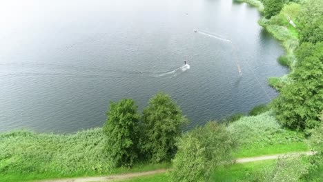 drone shot over nature to a person wakeboarding at water sport park