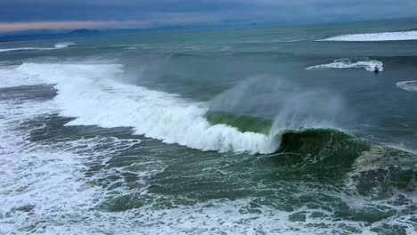 surfer catches and rides a large barreling wave in hossegor, france at sunrise on a winter morning