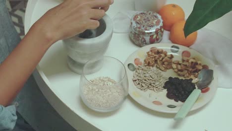 vista aérea de la molienda de semillas de lino con un mortero de piedra y un pestillo como parte de la preparación de avena para un desayuno saludable y una rutina matutina tranquila