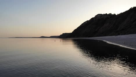 aerial above calm tranquil sunset waters beside littlecombe shoot beach