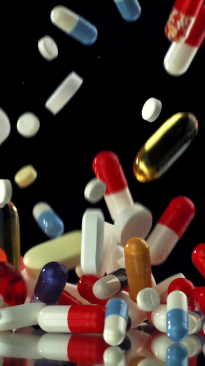 Colorful Pills and Capsules Falling in Slow Motion on Black Background