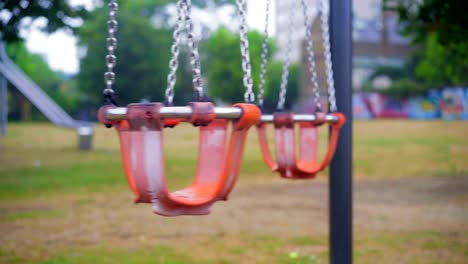 Kinderstuhlschaukel,-Die-Sich-Langsam-Auf-Einem-Leeren-Parkspielplatz-Bewegt,-Lockdown-Leere-Szene