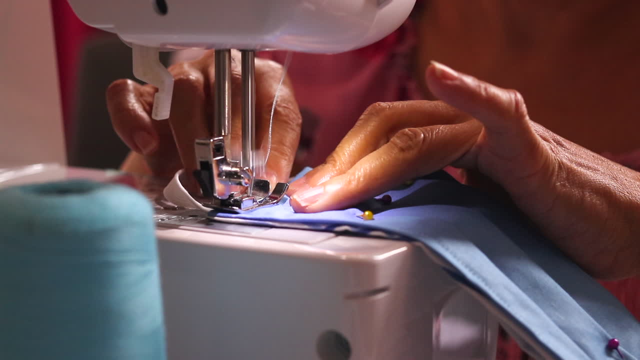 Close Up of Hands Operating a Sewing Machine with Blue Fabric