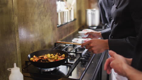 biracial male chef preparing a dish and smiling in a kitchen