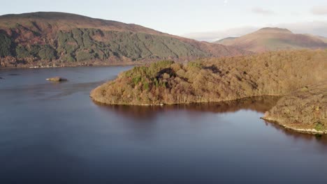 Linke-Rolle-Mit-Drohnenaufnahmen-Aus-Dem-Rechten-Schwenk,-Die-Ben-Lomond,-Beinn-Dubh-Und-Beinn-Bhreac-Mountains-Während-Eines-Herbstsonnenaufgangs-Mit-Einheimischen-Laubwäldern-Und-Loch-Lomond-Im-Vordergrund-Zeigen