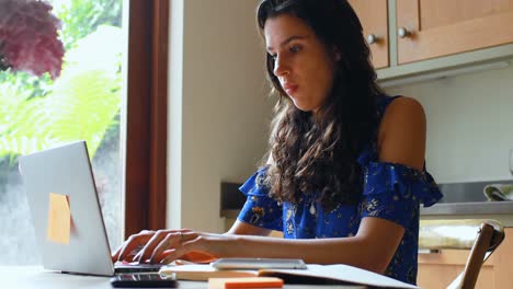 Woman-using-laptop-in-kitchen-4k