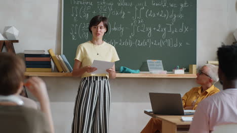 female student reciting lesson in front of classmates and teacher