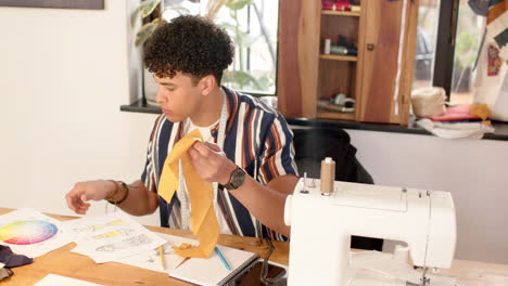 diseñador de moda masculino biracial diseñando ropa en el estudio, en cámara lenta