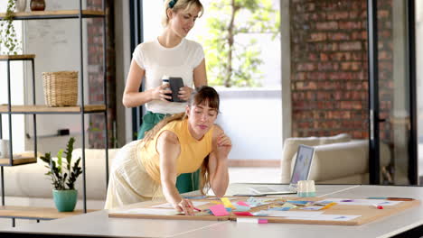 collaborating on creative writing, women using laptop and sticky notes in office
