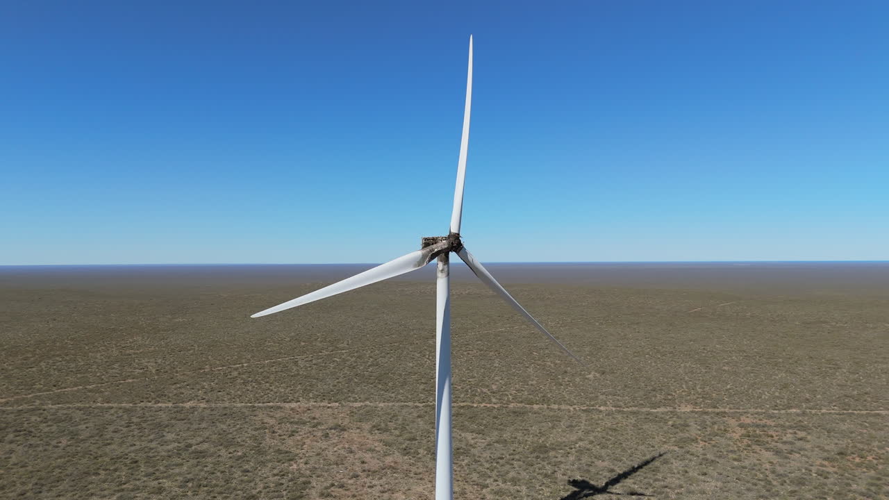 Slow-motion aerial close view of a damaged windmill still functioning.