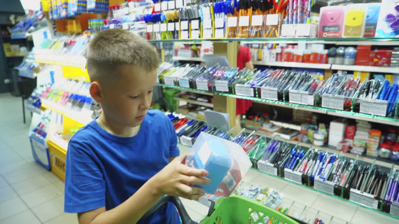 VINNITSA, UKRAINE - AUGUST 20, 2018: Beautiful boy choosing school stationery at a supermarket. Shopping for school