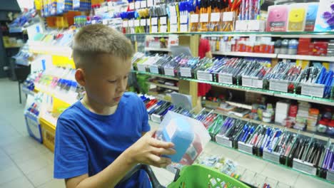 vinnitsa, ukraine - august 20, 2018: beautiful boy choosing school stationery at a supermarket. shopping for school