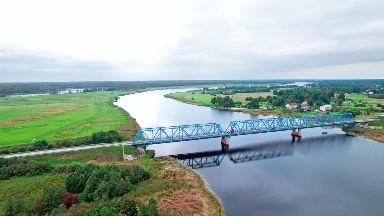 Bridge crossing a tranquil river in rural Latvia during cloudy weather