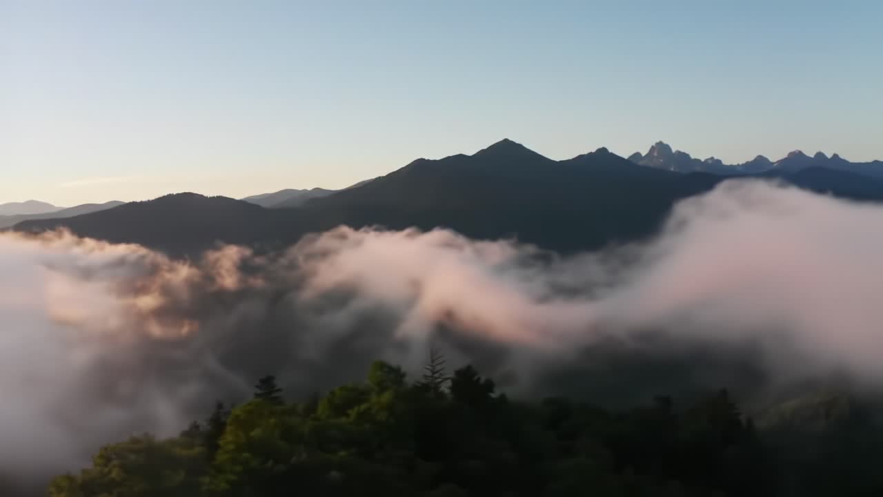 Early morning reveals a stunning vista where mist rolls over mountainous terrain as the sun rises, casting soft light and creating a serene atmosphere in nature's embrace.
