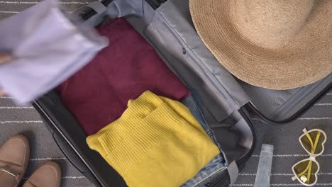 la mujer empaca la maleta lista para ir de vacaciones o vacaciones anticipadas. lanzar cosas y ropa en la bolsa del armario.