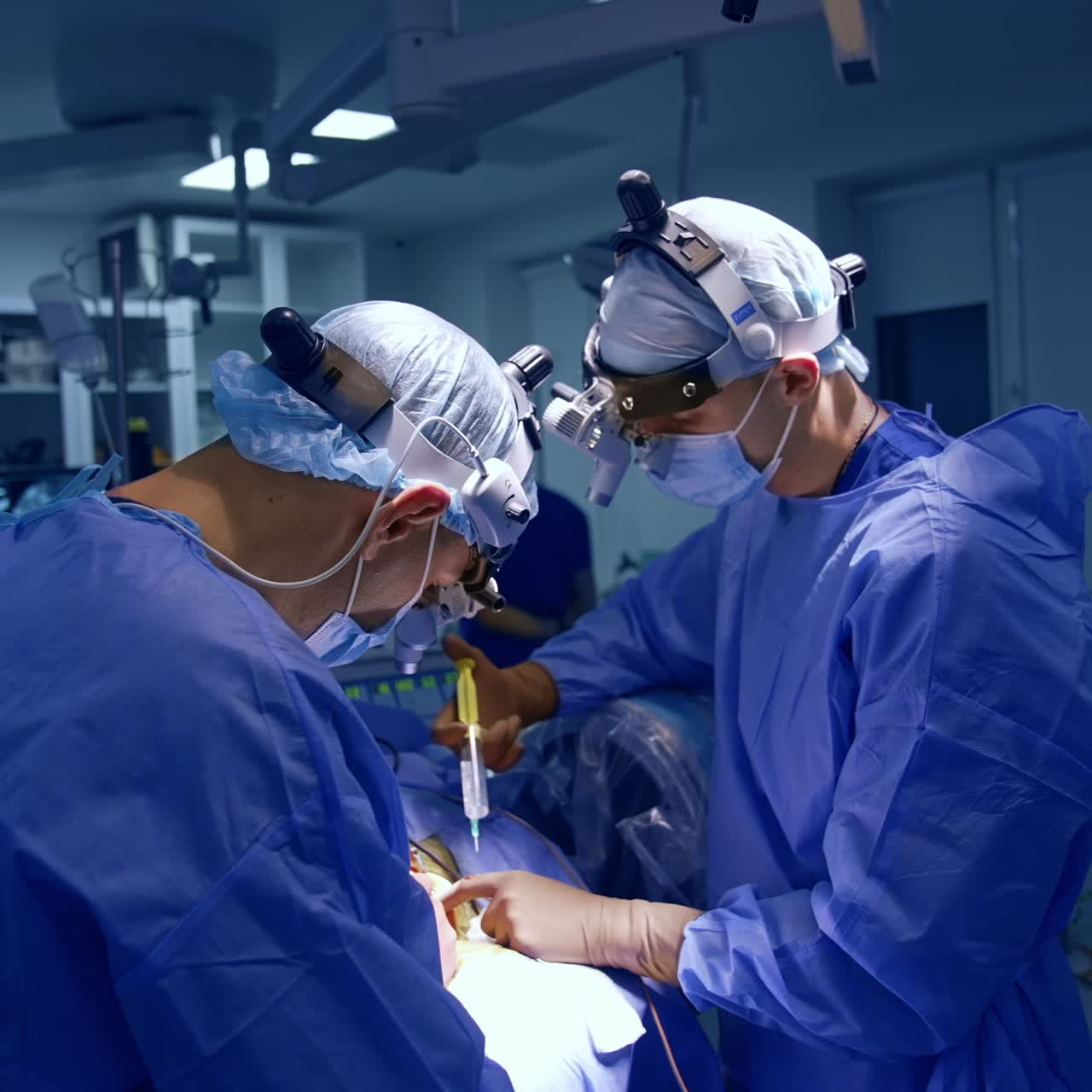 Surgeons wearing device glasses perform neurosurgery. Doctor uses syringe at operation. Modern surgical room backdrop