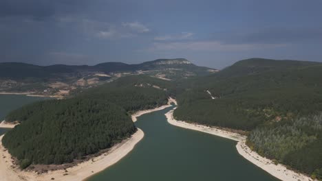 una impresionante vista aérea de un río sinuoso que atraviesa colinas boscosas, rodeado de terreno montañoso