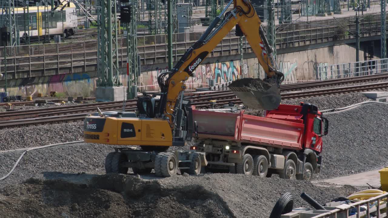 Excavator digging and loading gravel onto truck in front of railways Stuttgart 21