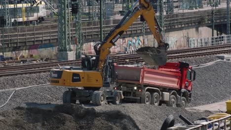 excavator digging and loading gravel onto truck in front of railways stuttgart 21