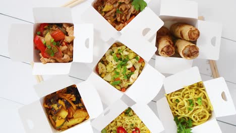 various oriental dishes packed in paper box  food is delivered on the table  asian take away concept