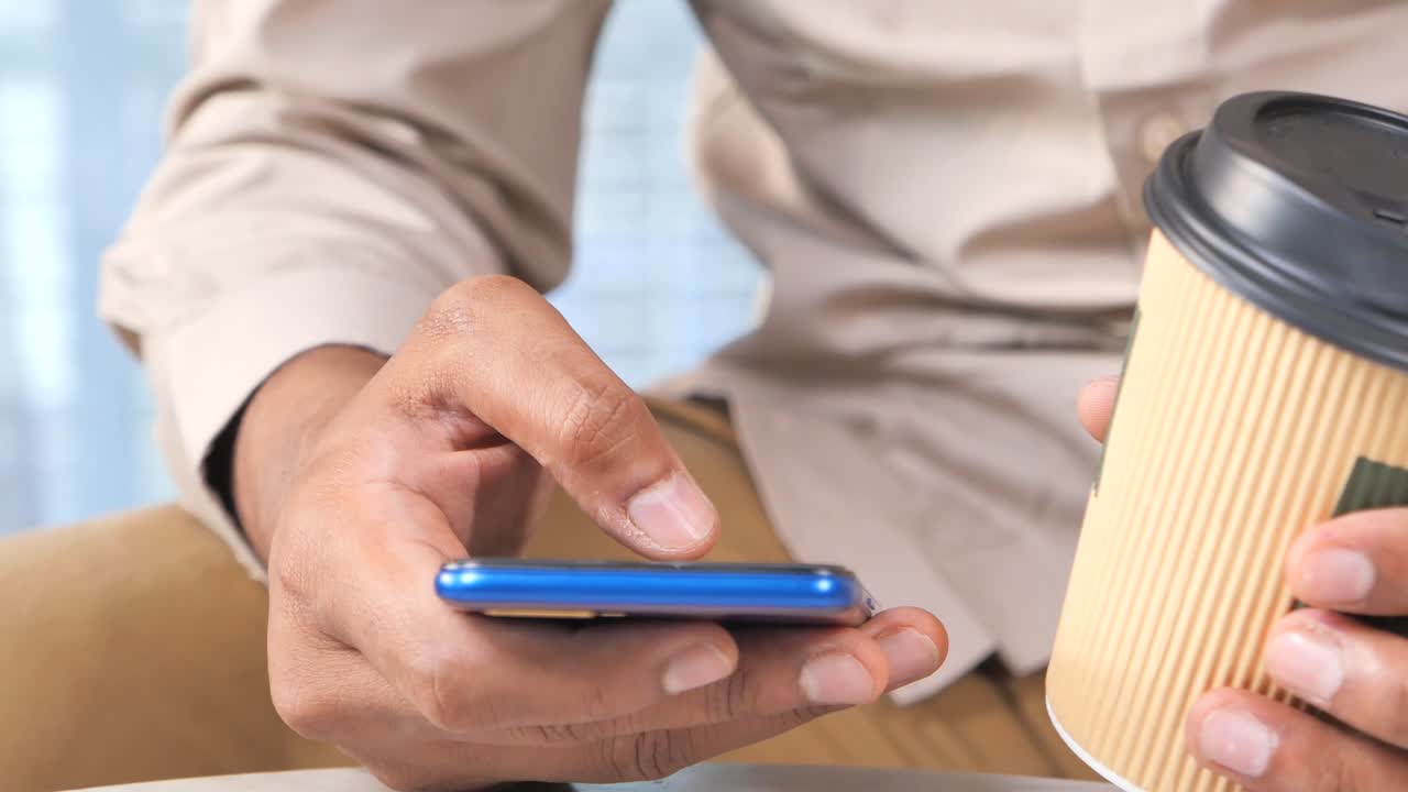 hombre usando teléfono inteligente y bebiendo café