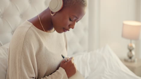 Black-woman,-headphones-and-writing-on-bed