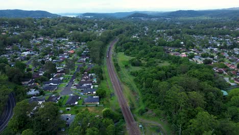 Drohnen-Luftbild,-Szenerie,-Zuglinie,-Eisenbahnstrecke,-Pendeln,-Stadtverkehr,-Buschland,-Vorstadt,-Metropole,-Niagara-Park,-Narara,-NSW,-Zentralküste,-Australien,-4k