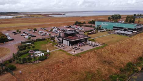 Toma-Aérea-Del-Restaurante-Holandés-Zoet-De-Zout-Y-área-De-Estacionamiento-Con-Autos-Estacionados-Y-Vehículos-Que-Se-Cruzan-Entre-Sí-A-Través-De-La-Carretera-Al-Lado-Del-Puerto