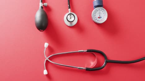 video of stethoscope with sphygmomanometer on red background with copy space