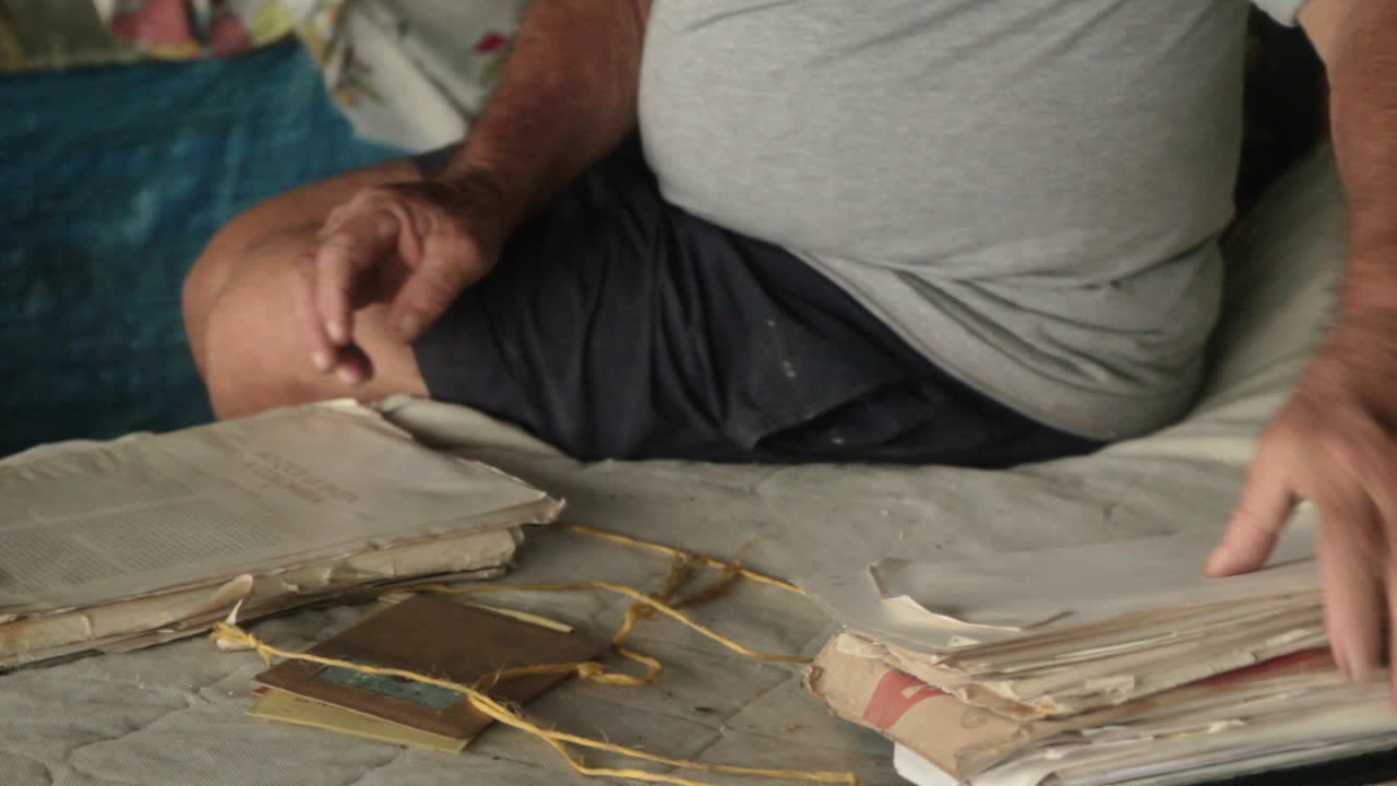 Old hands sift through faded documents, stories lived and written in coastal exile at the Darien Gap - Colombia
