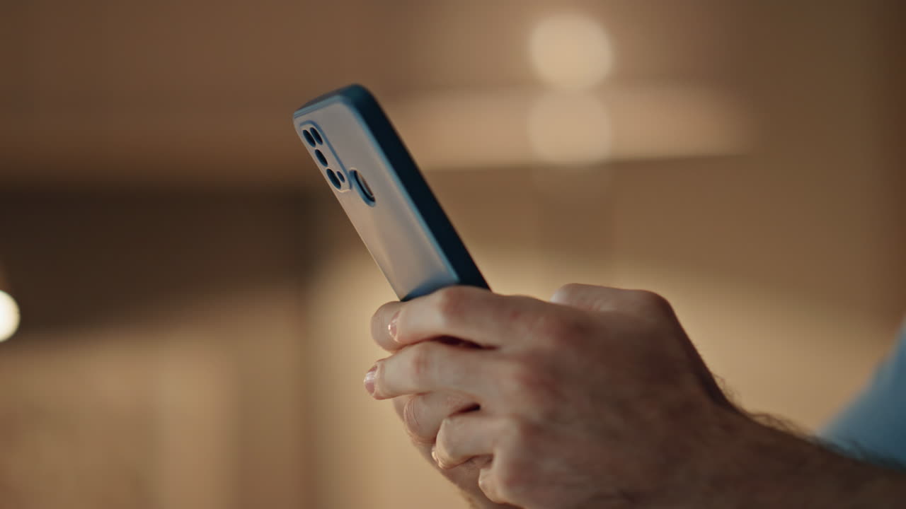 Man hands texting smartphone in evening apartment close up. Unrecognizable guy